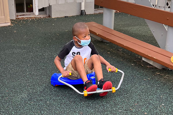 Princeton Nursery School boy on scooter toy